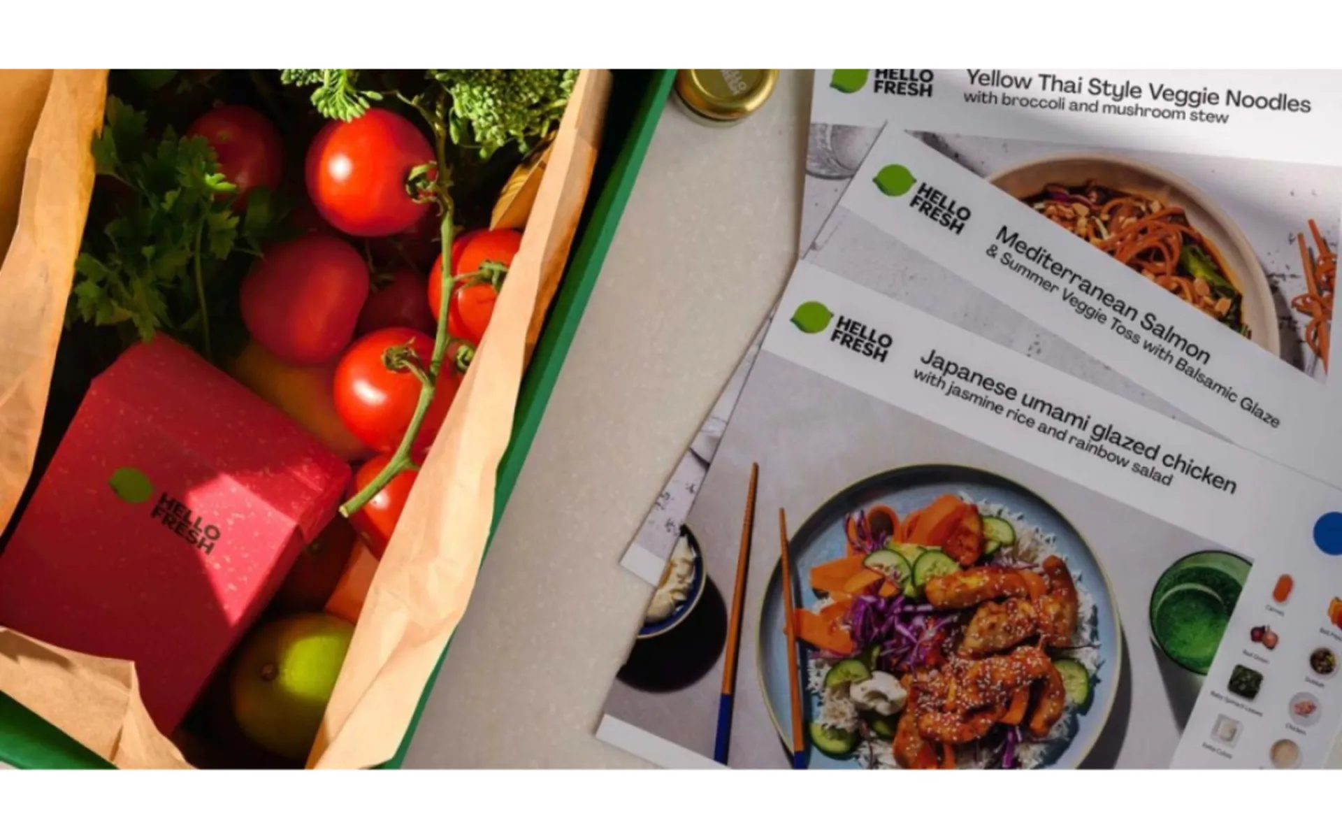 HelloFresh meal kit box filled with fresh produce, including tomatoes and herbs, alongside recipe cards featuring a selection of prepared meal options.