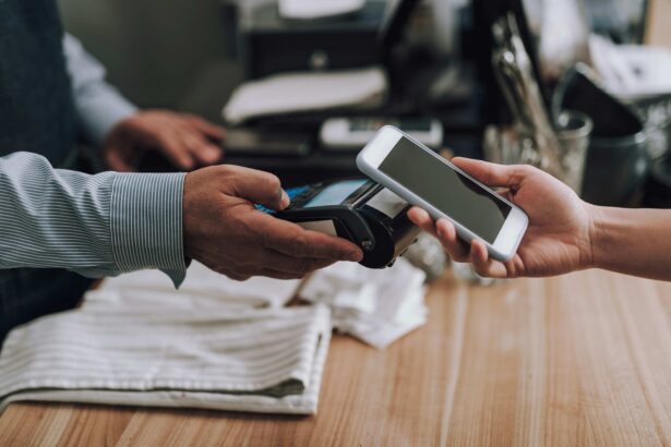 A customer holds a smartphone near a payment terminal to make a contactless payment at a retail checkout counter.
