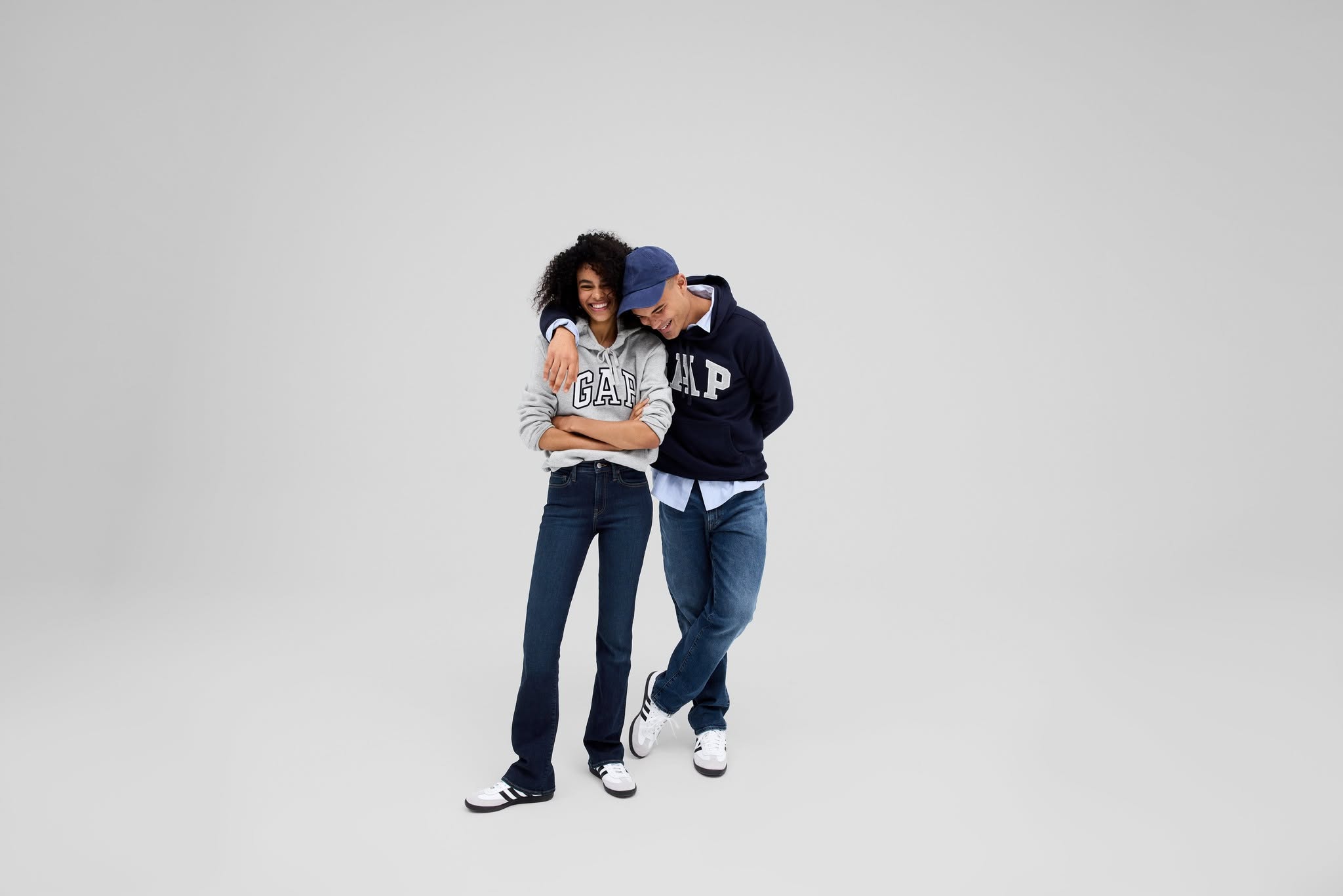 Two models wearing Gap hoodies and jeans pose together against a light grey background.