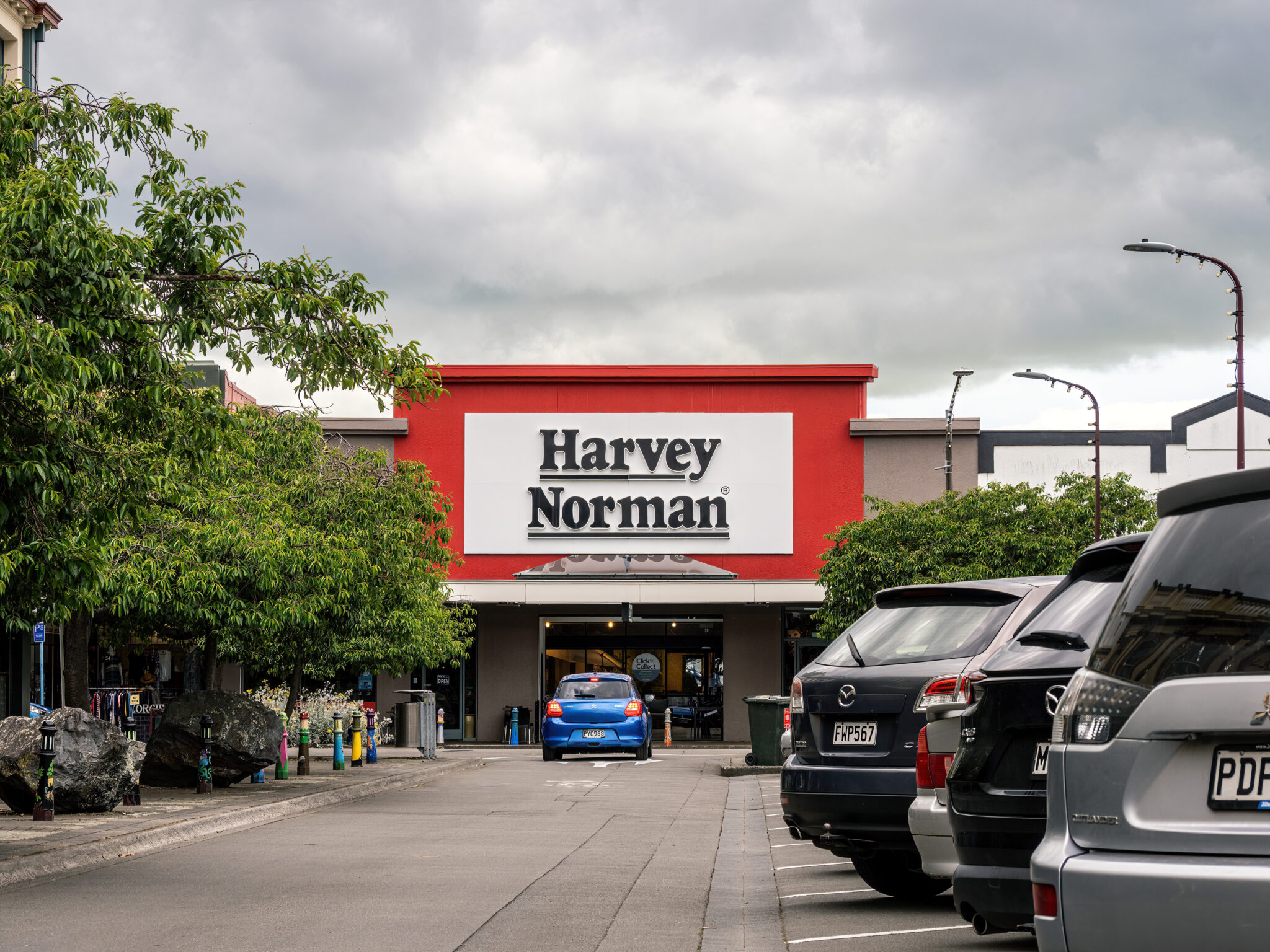 Exterior of a Harvey Norman store with cars parked outside.