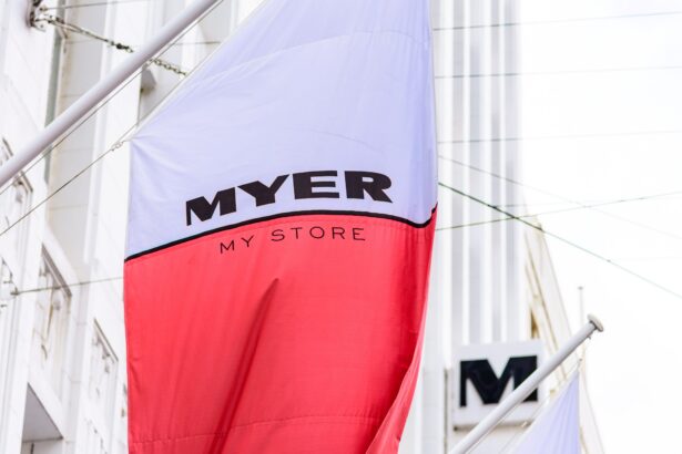 Close-up of a Myer department store flag displayed outside a city retail location, featuring the "MYER My Store" branding against the building façade, representing Australian retail and in-store shopping.
