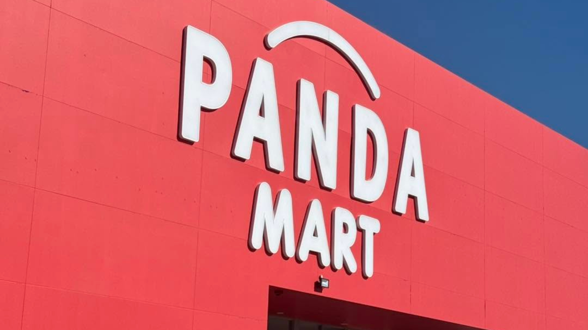 Exterior of a Panda Mart store, featuring the retailer’s white logo on a bright red facade against a blue sky.