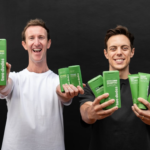 Two men holding a range of Two Dudes personal care products.